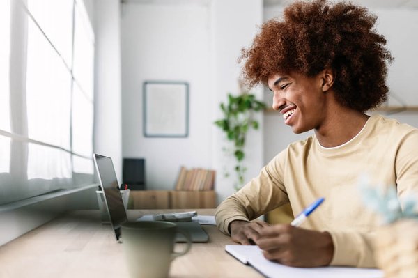Man taking notes by laptop