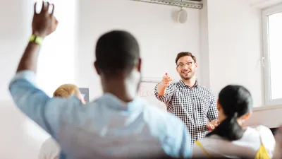 An education leader selects a student with his hand raised.