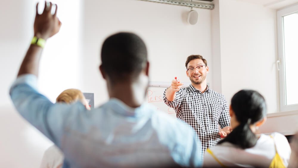An education leader selects a student with his hand raised.