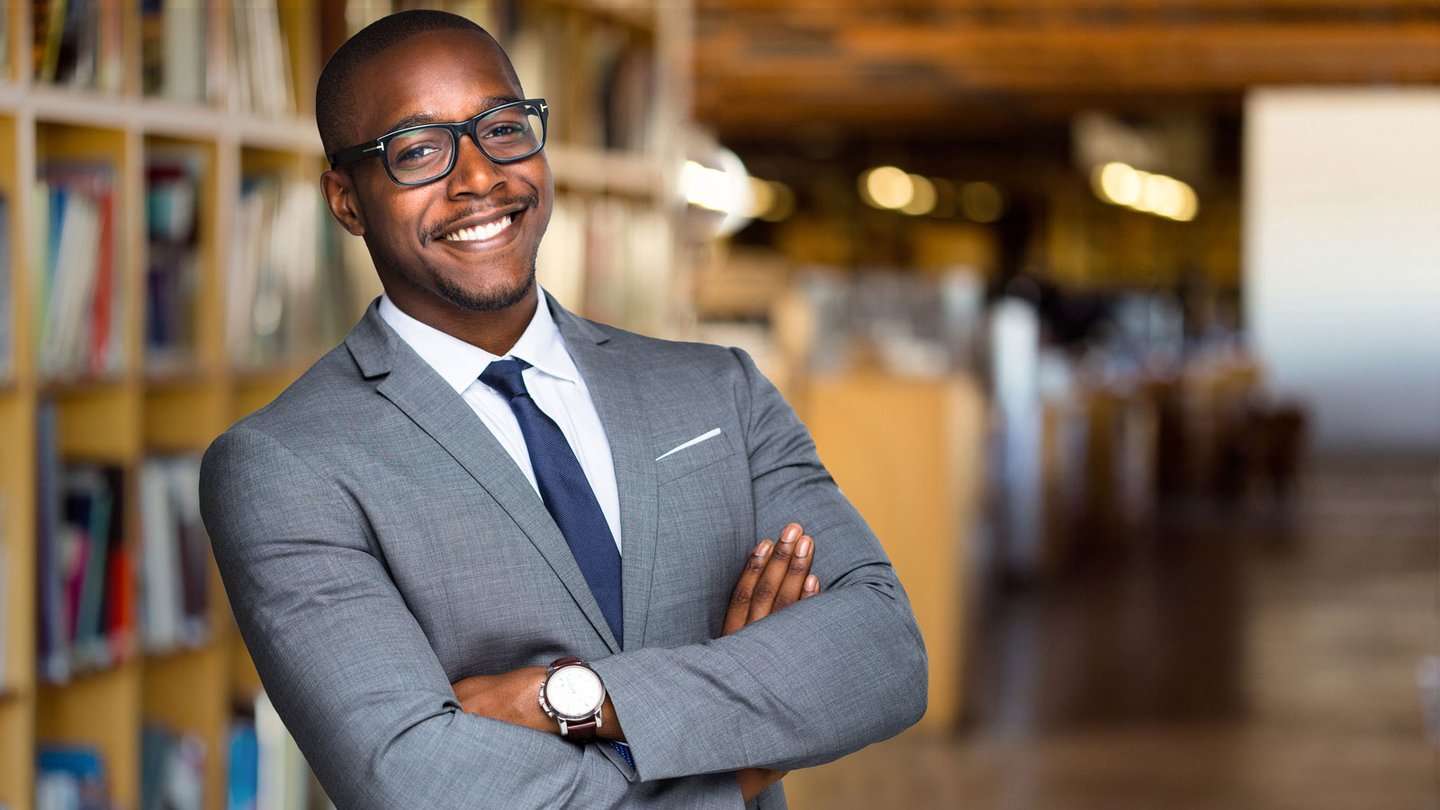 Confident smiling educator standing in library