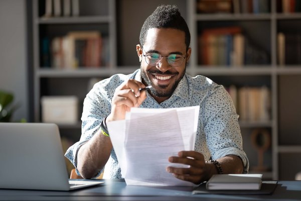 African American man looking at notes and studying in front of laptop