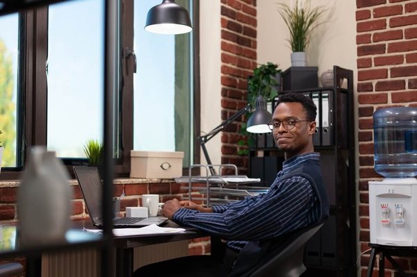 Young male professional sitting at desk smiling at camera